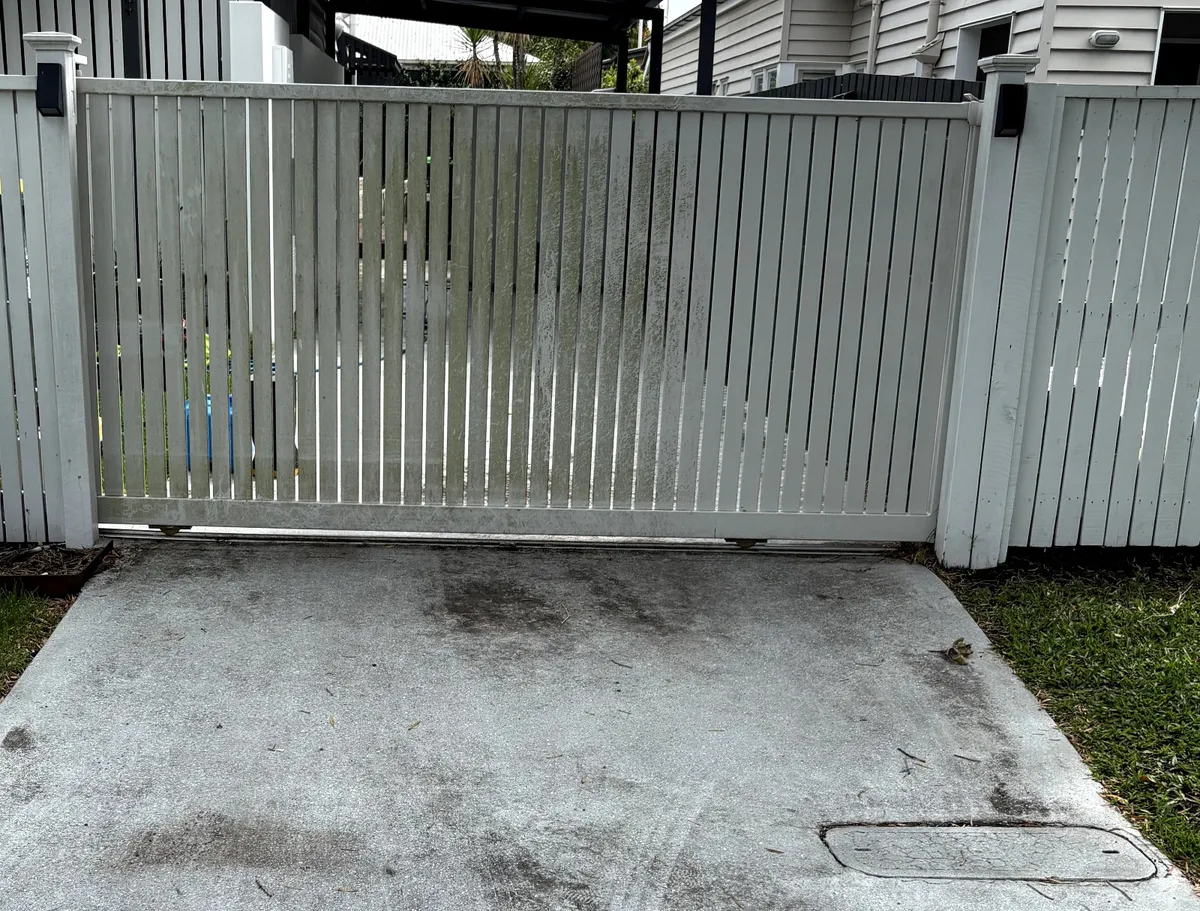 Driveway gate and concrete before pressure washing — grimy and algae-stained